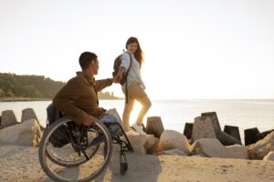 سفر راحت با استفاده از ویلچر مسافرتی، فرد معلول روی ویلچر همراه با همسرش کنار دریا 