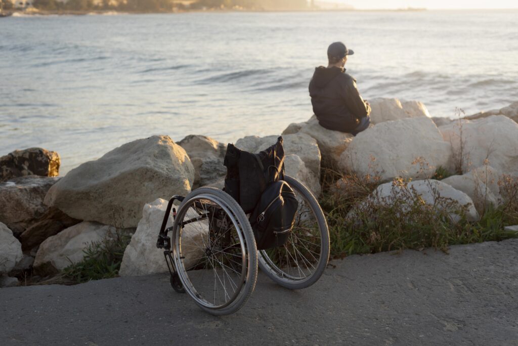ویلچر مسافرتی و فرد معلول در کنار دریا
